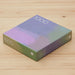 A 1000-piece jigsaw puzzle box with a purple, pink, and green gradient design, resting on a light wood grain surface.