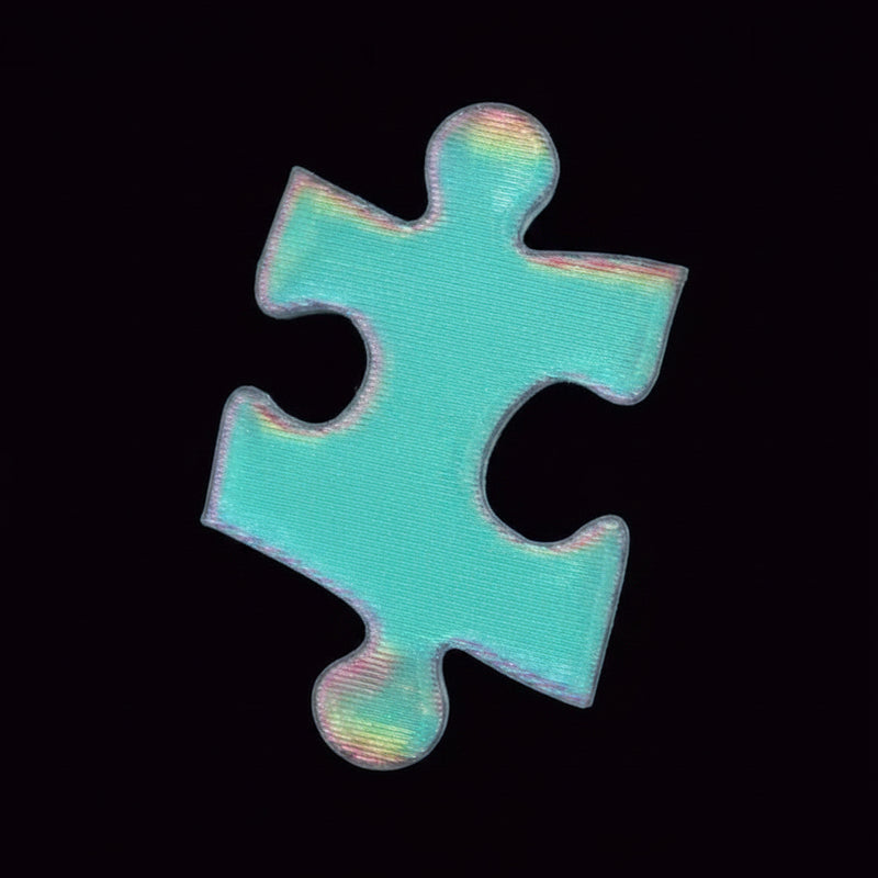 A single jigsaw puzzle piece with a holographic, iridescent light blue finish, held between two fingers against a solid black background.
