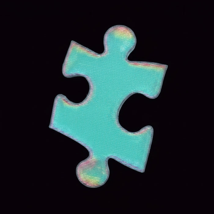 A single jigsaw puzzle piece with a holographic, iridescent light blue finish, held between two fingers against a solid black background.