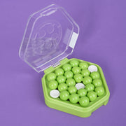 Green and white beads in a green container with a clear lid on a purple background