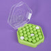Green and white beads in a green container with a clear lid on a purple background