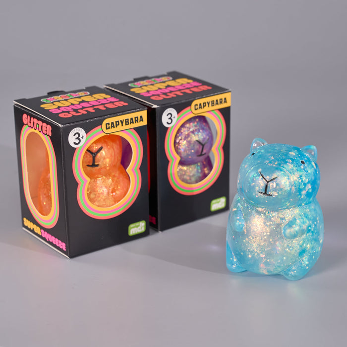Two boxed Capybara Glitter Squeezies by Pop Mart alongside a blue glittery Capybara squeeze toy on a neutral gray background.