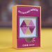 A boxed craft product labeled 'SPECTACULARLY MAGNETIC' with a visible hexagonal bead-like pattern in pink and beige, shown in its orange and magenta retail packaging on a yellow surface.