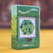 A green product box labeled 'SPECTACULARLY MAGNETIC' with a clear window showing a hexagonal cluster of small magnetic beads in green and yellow, photographed on a yellow surface with a blurred brown background.