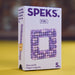 A box of SPEKS. 8 Bit rare earth fidget magnets, featuring a white box with purple branding and an image of a square frame built from purple and lavender magnetic beads, set against a yellow surface and blurred brown background.