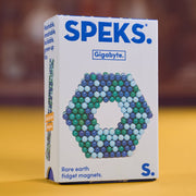 A box of SPEKS. Gigabyte Rare earth fidget magnets, model S, standing on a yellow surface with a blurred brown background.