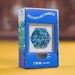 A blue product box for a magnetic item, featuring pixel-style green and white graphics on the side and a clear window showing a hexagonal magnetic piece with the brand name 'SPEKS' on it. The box is photographed on a yellow surface with a blurred brown background.
