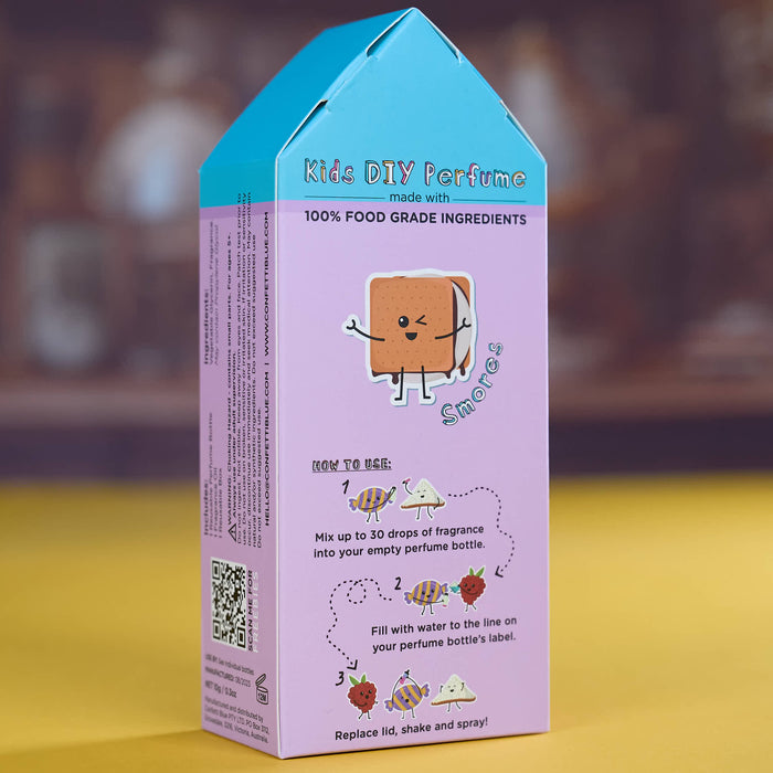 A house-shaped cardboard box for kids DIY perfume, featuring a light purple body with a bright blue top, cartoon graphics, and step-by-step instructions on how to make the perfume. The box is photographed standing upright on a yellow surface with a blurred brown background.