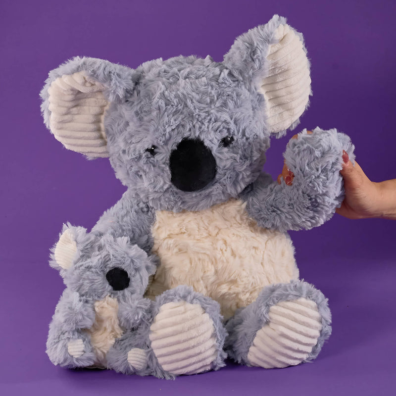 Grey koala plush toy, soft fluffy texture, cream belly and inner ears, large black nose, cute cuddly design, matching baby koala plush, cosy bedroom setting, warm soft lighting, Australian animal stuffed toy.