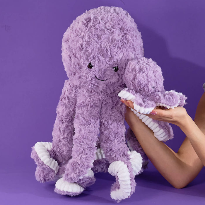 Purple plush octopus, soft fluffy texture, lavender color, cute smiling face, long tentacles, white rope-detail accents, cuddly stuffed toy, raised display, close-up product focus.