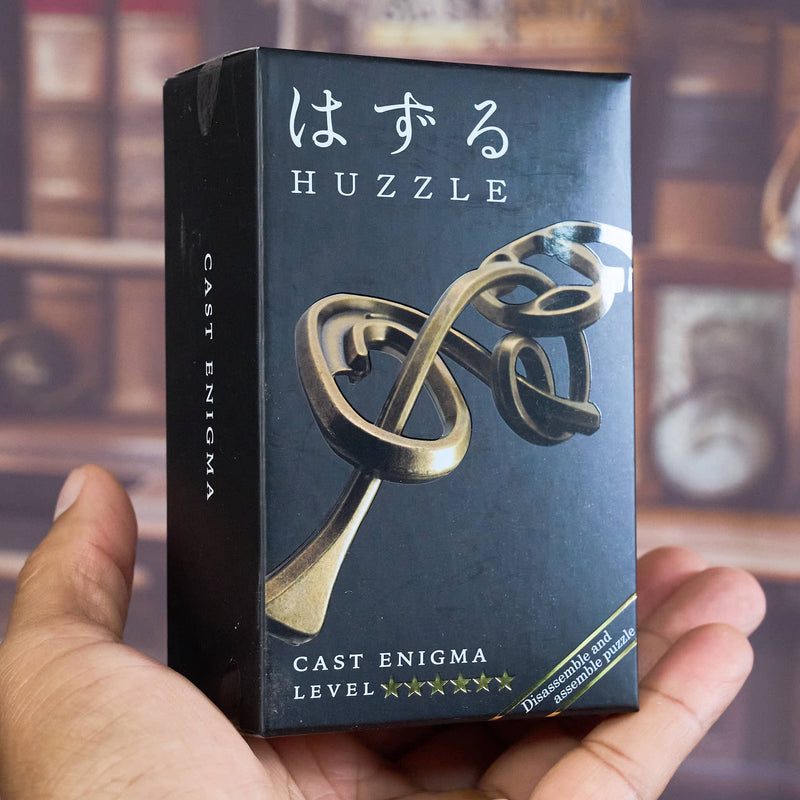 Huzzle Cast Enigma puzzle box held by a hand with a blurred background