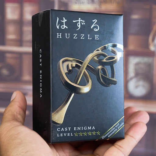 Huzzle Cast Enigma puzzle box held by a hand with a blurred background