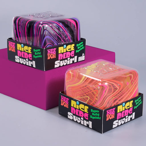 Two packaged squishy toys labeled 'Nice Berg Swirl' with black retail boxes, shown on a light gray background with a magenta display block. The front package contains a translucent orange, pink, and yellow marbled squishy; the rear package contains a translucent purple, pink, and black marbled squishy.