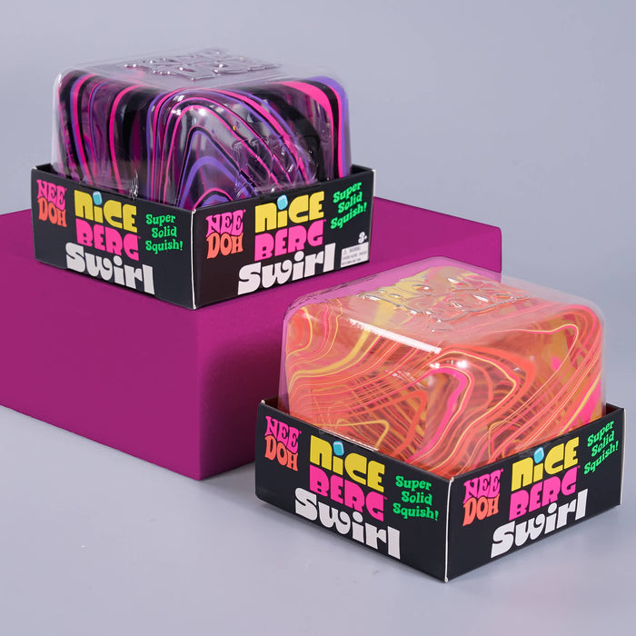 Two packaged squishy toys labeled 'Nice Berg Swirl' with black retail boxes, shown on a light gray background with a magenta display block. The front package contains a translucent orange, pink, and yellow marbled squishy; the rear package contains a translucent purple, pink, and black marbled squishy.