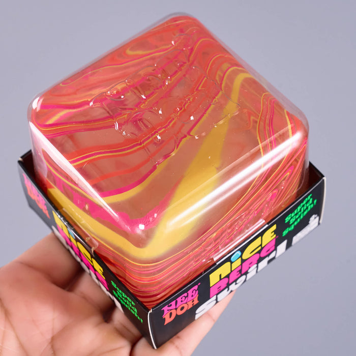 A hand holds a square plastic container filled with translucent pink, red, and yellow gel-like material. The box has colorful branding text, including 'New Dog' and 'Nice Berg Swirl'