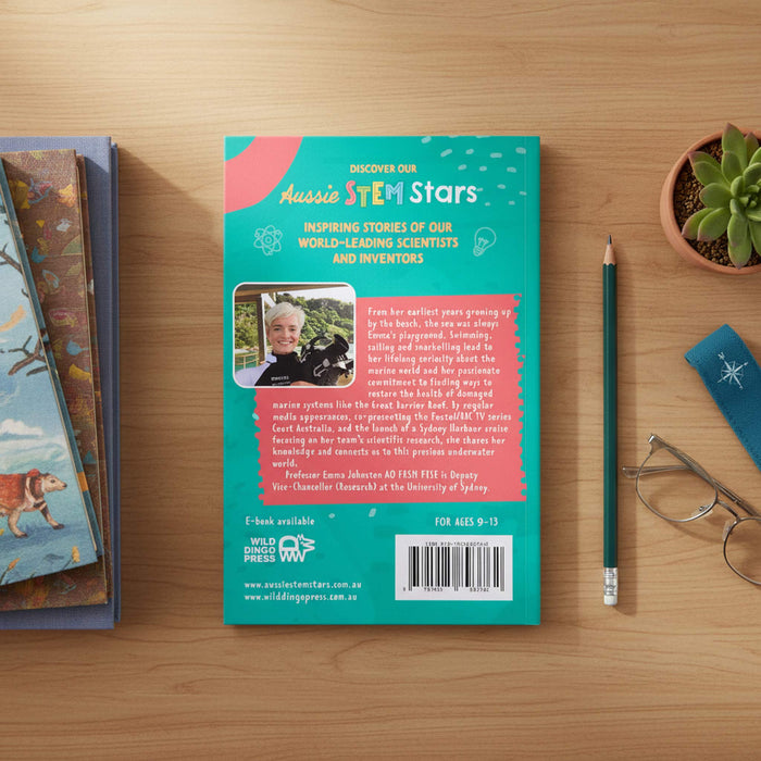 The back cover of a book titled 'Aussie STEM Stars' by Professor James Ridley is displayed on a light wood desk, surrounded by a pencil, a small potted succulent, and another book.