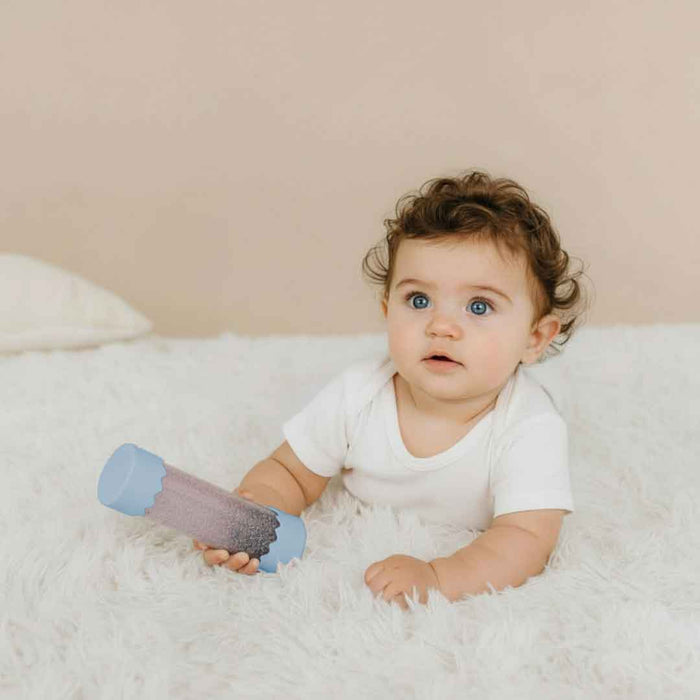 Baby holding a calm down bottle on a soft surface