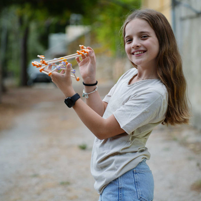 Young girl holding a toy gun outdoors with a blurred background