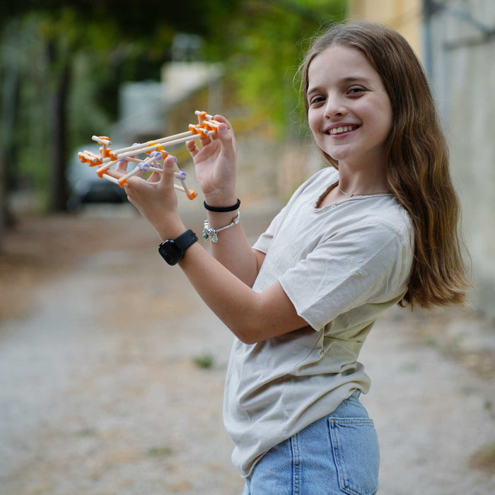 Young girl holding a toy gun outdoors with a blurred background