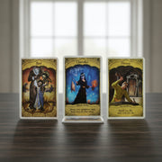 Three tarot cards with different designs on a wooden surface.