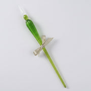 Green glass candle with a silver bow on a white background