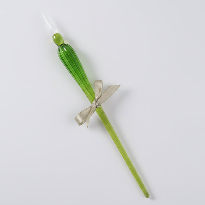 Green glass candle with a silver bow on a white background