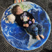 Young child laying on round Earth rug