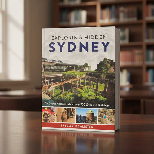 Book titled 'Exploring Hidden Sydney' by Trevor McAlistair on a table with a blurred bookshelf background.