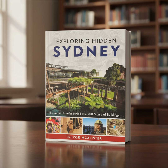 Book titled 'Exploring Hidden Sydney' by Trevor McAlistair on a table with a blurred bookshelf background.