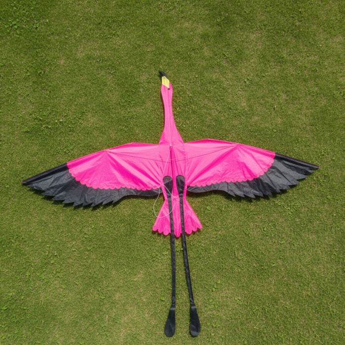 Pink flamingo kite with black wings on a grass background