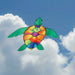 Colorful turtle-shaped kite flying against a blue sky with clouds