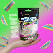 A hand holding a package of freeze-dried sour lollies with mini candy straps visible through the packaging.