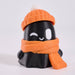 A 3D-printed cute ghost figurine wearing an orange knit beanie with a white pom-pom and an orange scarf, set against a plain light gray background.