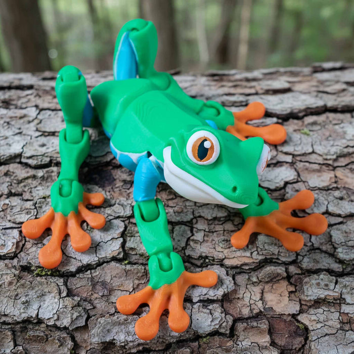 Toy frog on a tree branch with a natural background