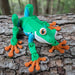 Toy frog on a tree branch with a natural background