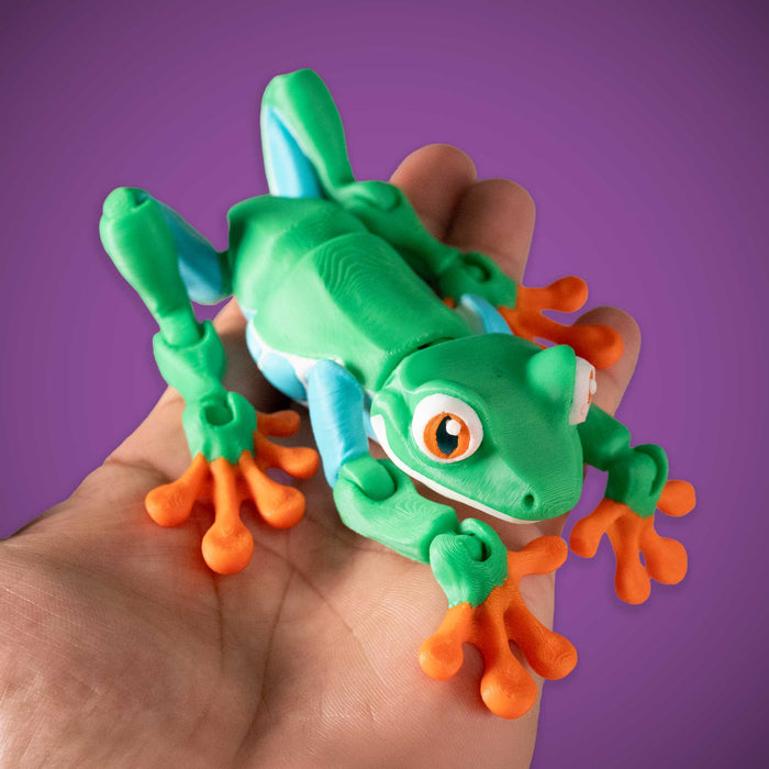 Toy frog held in a hand against a purple background