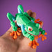 Toy frog held in a hand against a purple background