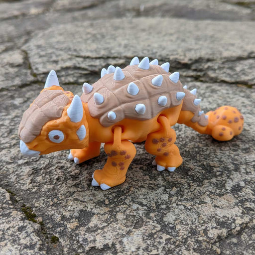 Toy dinosaur with orange body and beige back on a stone surface