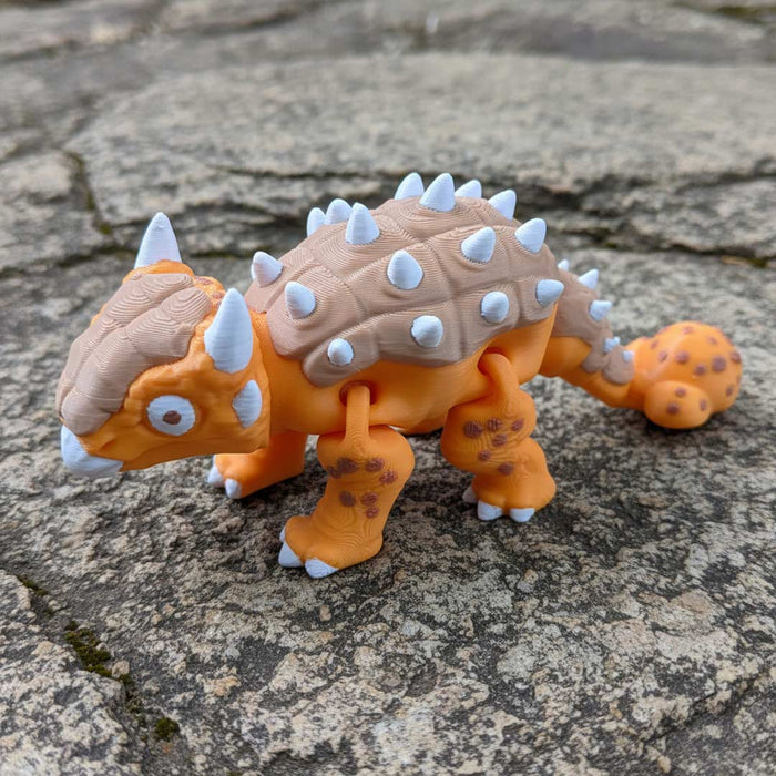 Toy dinosaur with orange body and beige back on a stone surface