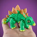 Toy dinosaur figure held in a hand against a purple background