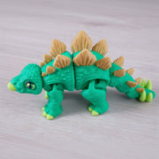 Toy dinosaur with green body and beige spikes on a light gray background