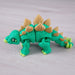 Toy dinosaur with green body and beige spikes on a light gray background