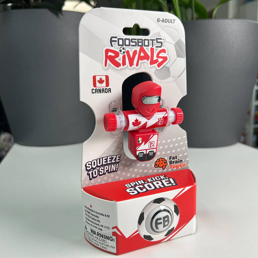 Red and white toy figure of canada in packaging with 'Foosbots Rivals' branding on a neutral background.