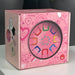 Introduce your little one to rhythm and colour with the Baby Pink box with colorful letter 'U' design on a gray background
