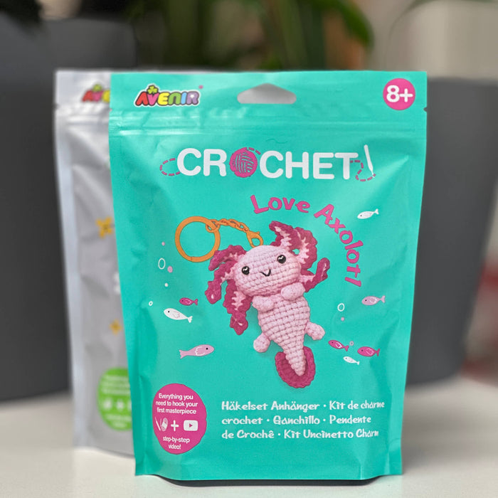 Crochet kit packaging with a pink axolotl design on a teal background