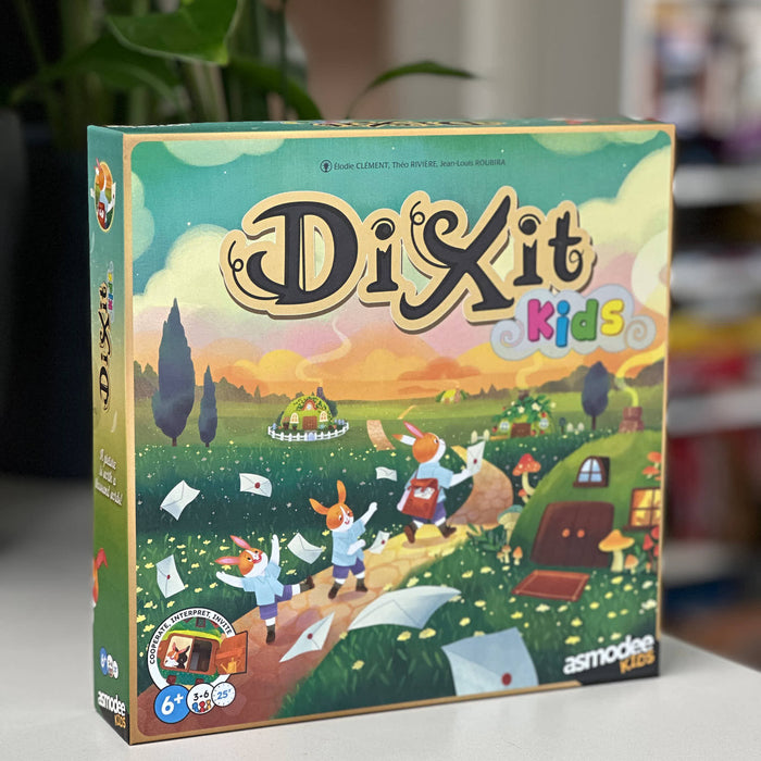 Board game box for 'Dixit Kids' by Asmodee on a surface with a blurred background