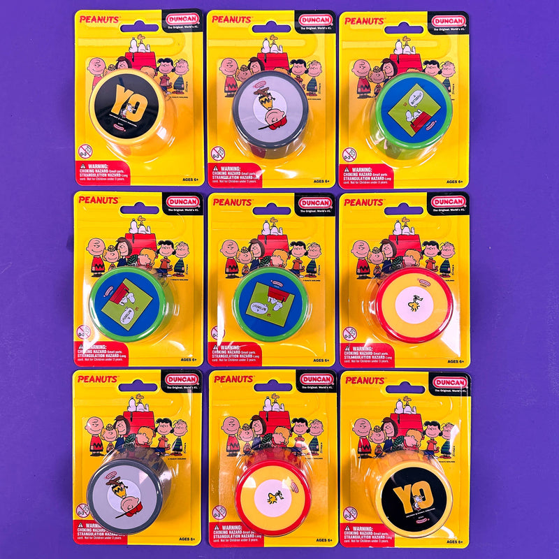 Set of eight 'Peanuts' yo yo duncan themed tape measures in packaging on a purple background