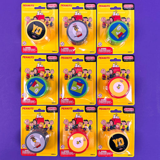 Set of eight 'Peanuts' yo yo duncan themed tape measures in packaging on a purple background