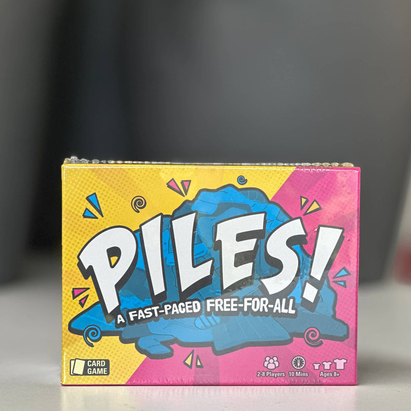 Board game box titled 'Piles!' with colorful design on a dark background
