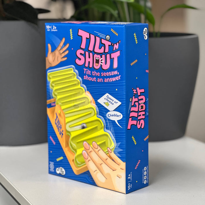 Tilt 'N Shout game box on a surface with plants in the background